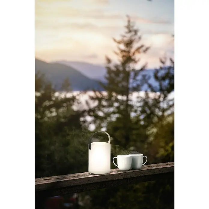 FHL easy Akku-Tischleuchte CIRO - 0,7 W, L x B x H: 11 x 11 x 15 cm, Weiß, RGB, 2 Stk. - Stimmungsvolle Szene mit einer tragbaren Lampe und zwei Tassen auf einer Holzbalustrade, ideal für gemütliche Abende im Freien.