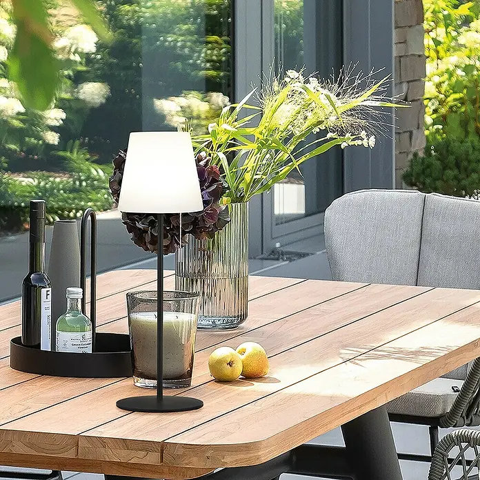 SCHÖNER WOHNEN-Kollektion Akku-Tischleuchte TALENT - 2 W, L x B x H: 12 x 12 x 38 cm, Sand, RGBW - Tischdekoration mit Lampe, Kerze, Blumenvase und zwei Birnen auf einem Holztisch im Freien.