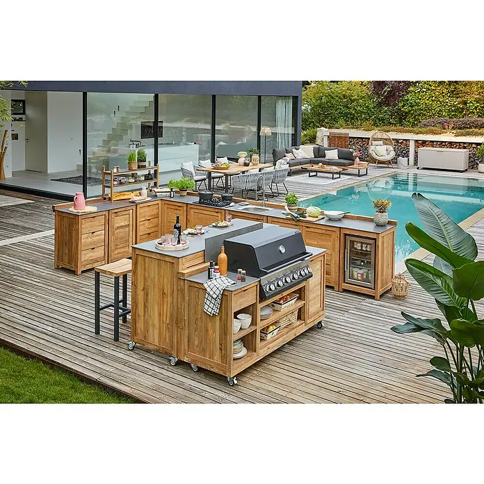 Sunfun Zoe Outdoorküchen-Modul Grillinsel - Braun, B x T x H: 188 x 67 x 96,7 cm, Teakholz - Ein Blick auf eine luxuriöse Outdoor-Küche aus Holz mit Grill, Spüle und Kühlschrank, die sich neben einem glitzernden Pool befindet.