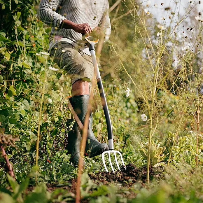 Fiskars Xact Spatengabel - Arbeitsbreite: 18,5 cm, Anzahl Zinken: 4, Langstiel - Person, die im Garten arbeitet mit einer Fiskars Gartengabel. Ideal zum Auflockern und Belüften von Böden.