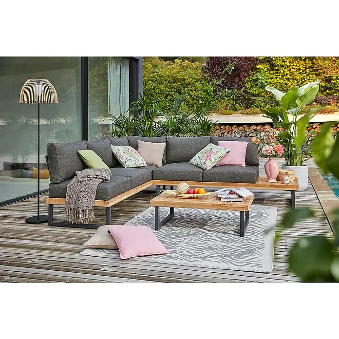 Sunfun Zoe Loungemöbel-Set - 3 -tlg., Teak/Stahl, Dunkelgrau - Ein modernes Gartenlounge-Set mit grauem Ecksofa, Holztisch und gemustertem Teppich auf einer Holzterrasse, ideal zum Entspannen im Freien.