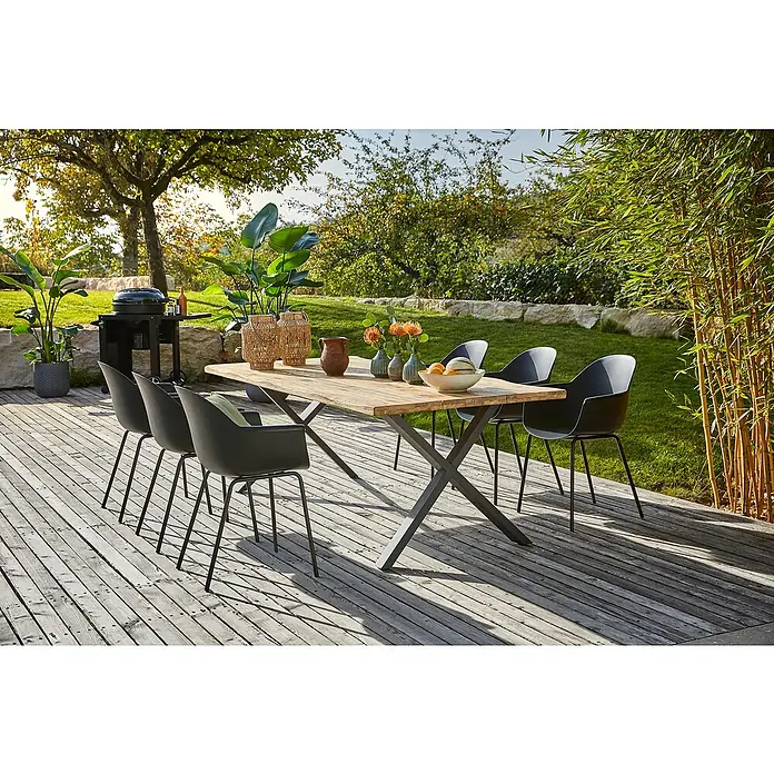 Sunfun Gartenmöbel-Set My - 8 -tlg., Baumkante/X-Gestell, Teak/Edelstahl/Kunststoff, Teak/Grau/Schwarz - Ein einladender Esstisch mit sechs schwarzen Stühlen auf einer Holzterrasse. Ideal für Mahlzeiten im Freien mit stilvoller Dekoration und Grill.