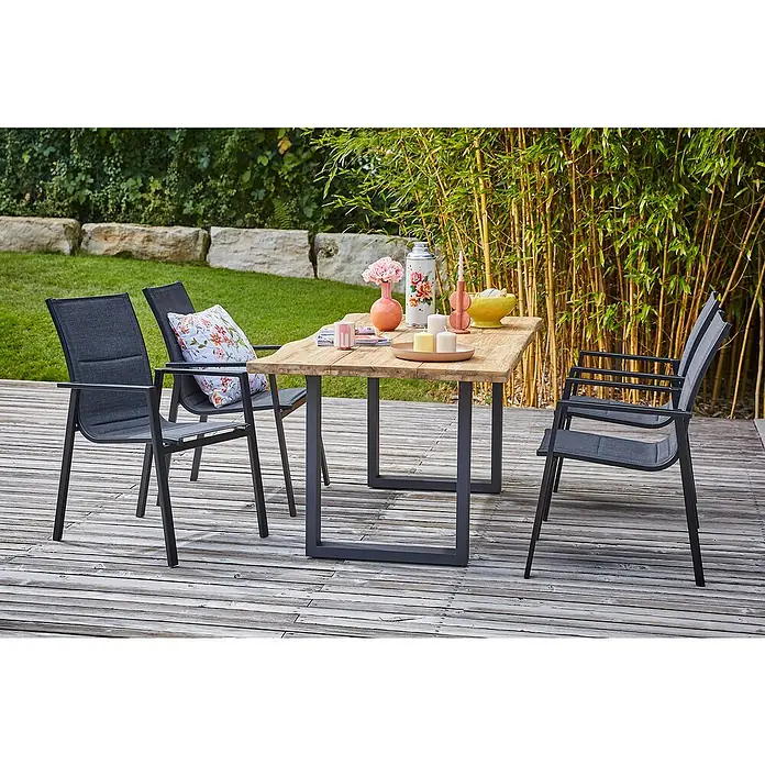 Sunfun Maja Gartenmöbel-Set - 6 -tlg., Baumkante/U-Gestell, Teak/Edelstahl/Textilen, Teak/Grau - Ein Gartentisch-Set mit vier Stühlen auf einer Holzterrasse, dekoriert mit Blumen und Kerzen, umgeben von Bambus und Grün.