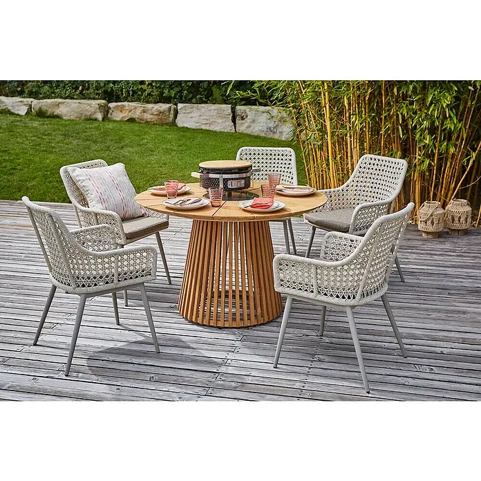 Sunfun Gartenmöbel-Set Osby/Zoe - 6 -tlg., Teak/Aluminium/Kunststoff, Teak/Sand - Gartenmöbel-Set mit einem runden Tisch und Stühlen aus Rattan auf einer Terrasse mit Holzdeck und Bambus im Hintergrund.