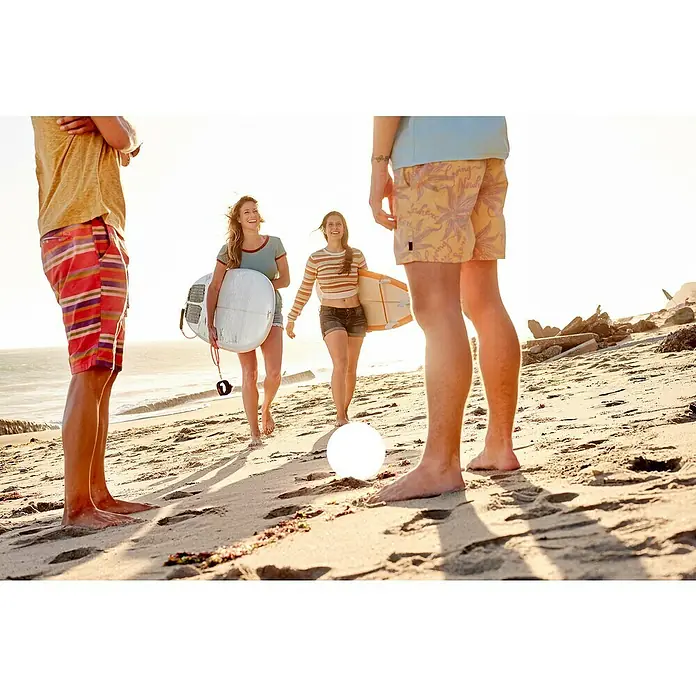 FHL easy Akku-Tischleuchte BUSSO - 0,1 W, L x B x H: 18 x 18 x 16 cm, Weiß, RGB - Strandfoto mit Personen und Surfbrettern im Fokus, ideal für Lifestyle- und Urlaubsstimmungen mit sommerlichen Elementen.