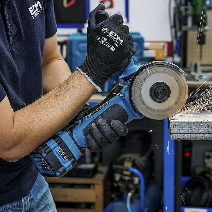 Koma Tools PRO Series Amoladora angular de batería - 1 batería, 4 Ah, Diámetro disco: 115 mm - Un trabajador utiliza una amoladora angular inalámbrica azul, creando chispas al cortar metal y usando guantes para protección.