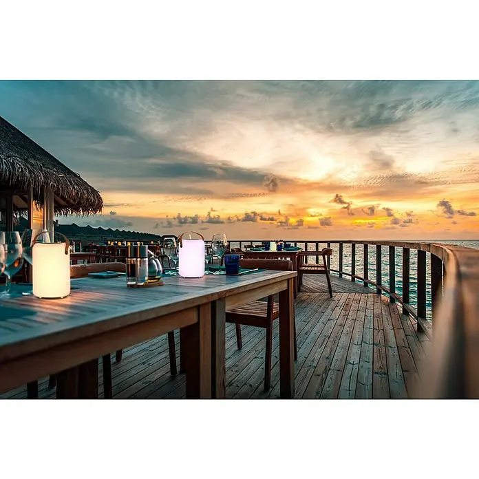 FHL easy Akku-Tischleuchte ORNO Solar - 0,5 W, L x B x H: 14 x 14 x 20 cm, Weiß, RGB, Solarbetrieben - Stimmungsvolle Tischleuchten auf einer Restaurantterrasse bei Sonnenuntergang. Die Leuchten sorgen für ein angenehmes Ambiente.