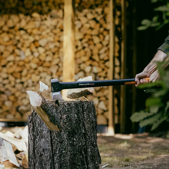 Fiskars X-series Spaltaxt X32 - Länge: 81,5 cm - Nahaufnahme einer Axt der Marke Fiskars beim Holzspalten, Holzspäne fliegen.