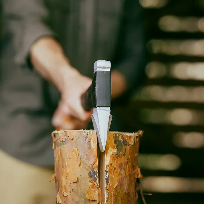 Fiskars X-series Spaltaxt X32 - Länge: 81,5 cm - Nahaufnahme eines Holzspalters, der in einen Holzscheit getrieben wurde, was die robuste Konstruktion und Effektivität des Werkzeugs hervorhebt.