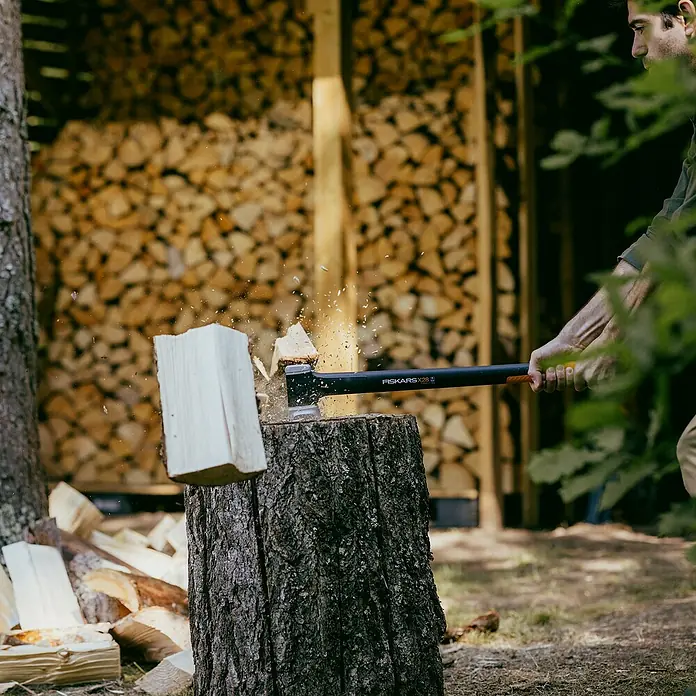 Fiskars X-series Spaltaxt X28 - Länge: 71 cm - Ein Mann spaltet Holz mit einer Fiskars X28 Spaltaxt. Die Axt ist gut ausbalanciert und effizient für größere Stämme.