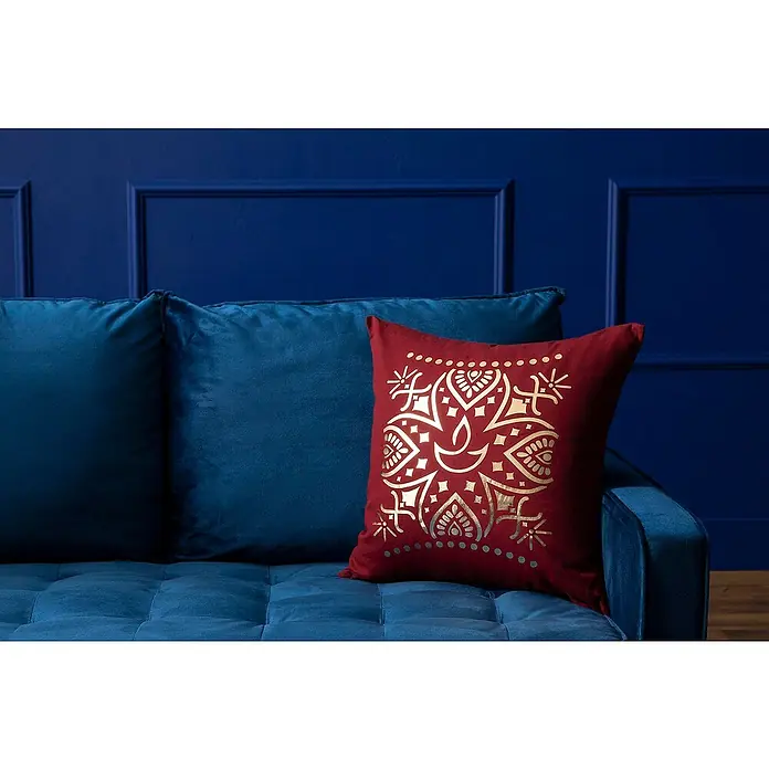 Cricut Maker Schneideplotter Maker 3 - Blau, Bluetooth, Schnittbreite: 29,7 cm, Schnittlänge: 3,6 m - Nahaufnahme eines burgunderroten Kissens mit goldenem Aufdruck auf einem blauen Sofa vor einer blauen Wand.