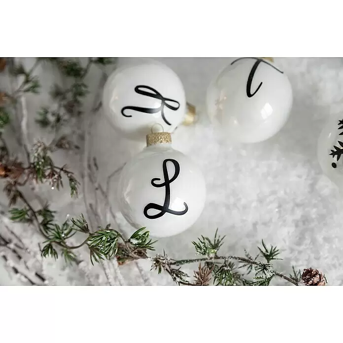 Cricut Joy Schneideplotter Smarte Schneide- und Zeichenmaschine - Türkis/Weiß, Bluetooth, Schnittbreite: 10,4 cm, Schnittlänge: 1,2 m - Weiße Christbaumkugeln mit schwarzen Buchstaben, auf Schnee mit Tannenzweigen.