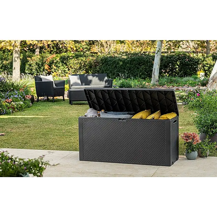 Keter Garten-Aufbewahrungsbox Emily - L x B x H: 117,8 x 44,6 x 58 cm, Graphite, Kunststoff - Ein offener, anthrazitfarbener Outdoor-Aufbewahrungskasten mit Kissen auf einer Terrasse mit Gartenmöbeln und Blumen.
