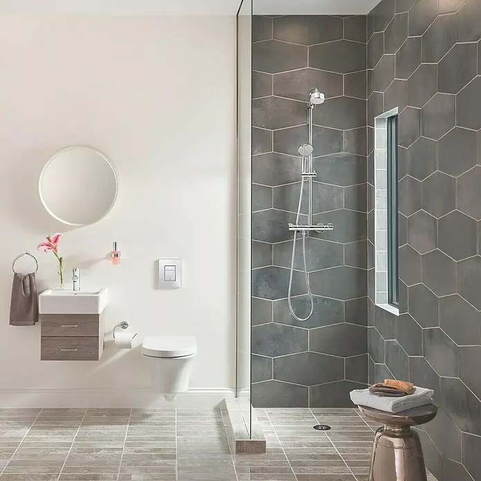 Grohe Essentials Handtuchring - Chrom, Glänzend - Ein stilvolles Badezimmer mit einer modernen Duschkabine mit grauen Fliesen, einem Waschbecken mit Spiegel und einer Toilette.
