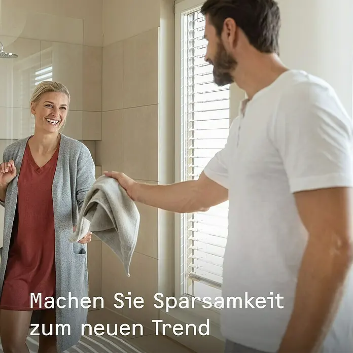Stiebel Eltron Durchlauferhitzer DHB 18/21/24 ST Trend - 18/21/24 kW, Elektronisch, Druckfest - Ein Mann reicht einer lächelnden Frau ein Handtuch im Badezimmer. "Machen Sie Sparsamkeit zum neuen Trend".