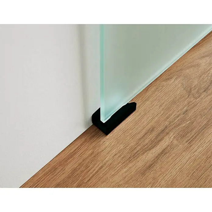 GME Puerta corredera de vidrio - 75 x 220 cm, Vidrio templado, Negro mate - Primer plano de una mampara de vidrio con un soporte negro sobre un suelo de madera, colocada contra una pared blanca.