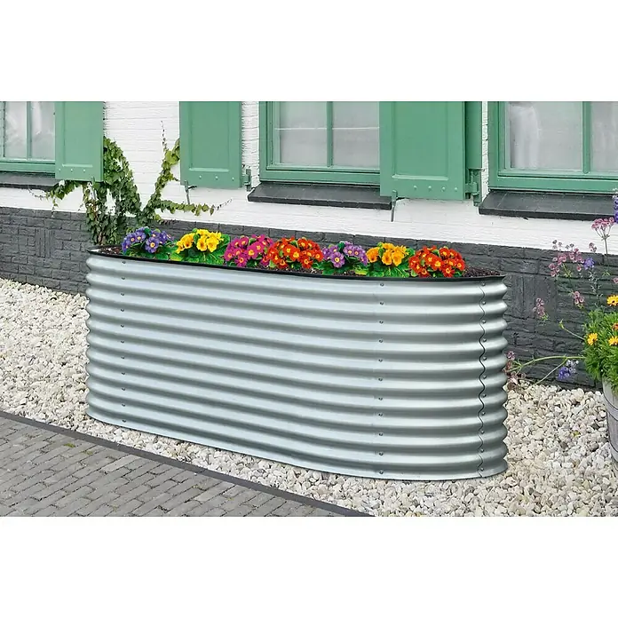 Floraworld Hochbeet Welle - 240 x 80 x 81,5 cm, Stahl, Silber - Ein erhöhter Pflanzkasten aus verzinktem Stahl mit bunten Blumen vor einer Hauswand.