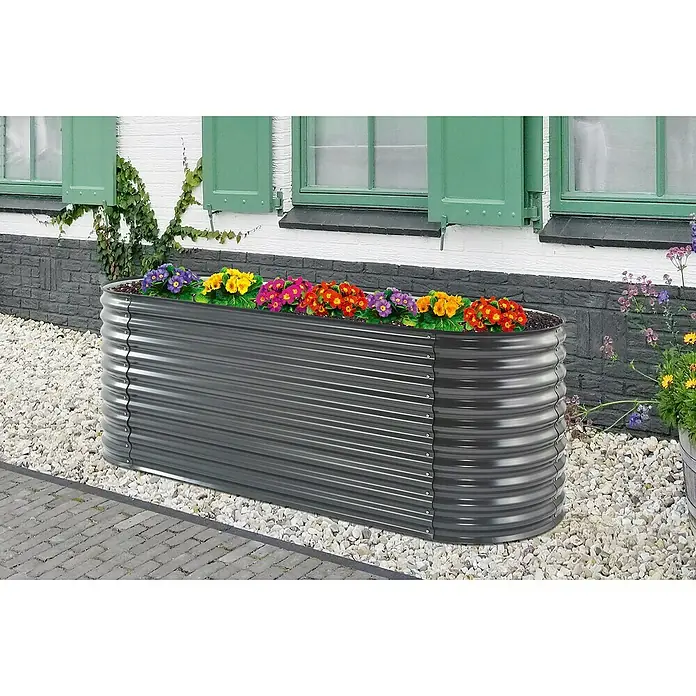 Floraworld Hochbeet Welle - 240 x 80 x 81,5 cm, Stahl, Anthrazit - Ein graues Hochbeet aus Metall mit bunten Blumen steht vor einem Haus. Das Beet ist ideal für den Anbau von Gemüse und Kräutern im Garten.