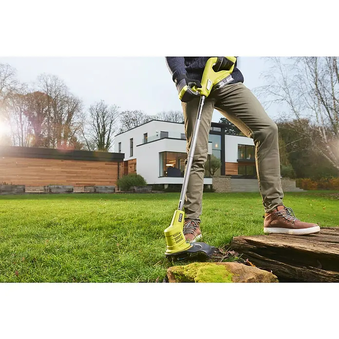Ryobi ONE+ Akku-Rasenmäher-Set Kombo-Kit RLM1833BLT1825M mit Akku-Rasentrimmer - 1 Akku, 4 Ah - Eine Person bedient einen Ryobi Akku-Rasentrimmer im Garten, umgeben von üppigem Grün und einem modernen Haus im Hintergrund.