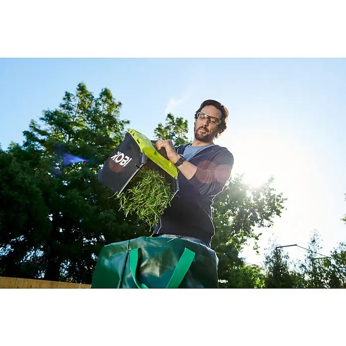 Ryobi ONE+ Akku-Rasenmäher-Set Kombo-Kit RLM1833BLT1825M mit Akku-Rasentrimmer - 1 Akku, 4 Ah - Mann leert einen Rasenmäherfangkorb von Ryobi in eine grüne Gartentüte.