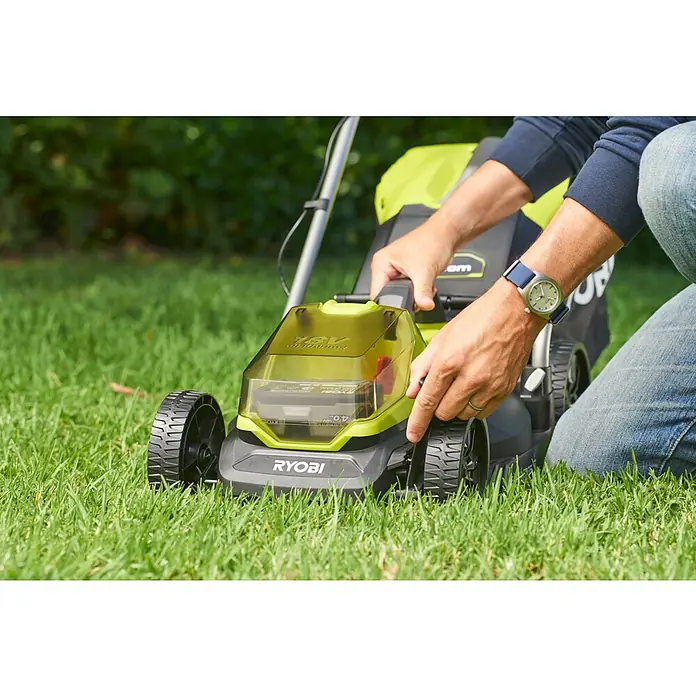 Ryobi ONE+ Akku-Rasenmäher-Set Kombo-Kit RLM1833BLT1825M mit Akku-Rasentrimmer - 1 Akku, 4 Ah - Nahaufnahme eines RYOBI Rasenmähers auf Gras, bedient von einer Person mit einer Armbanduhr, die den Rasen pflegt.