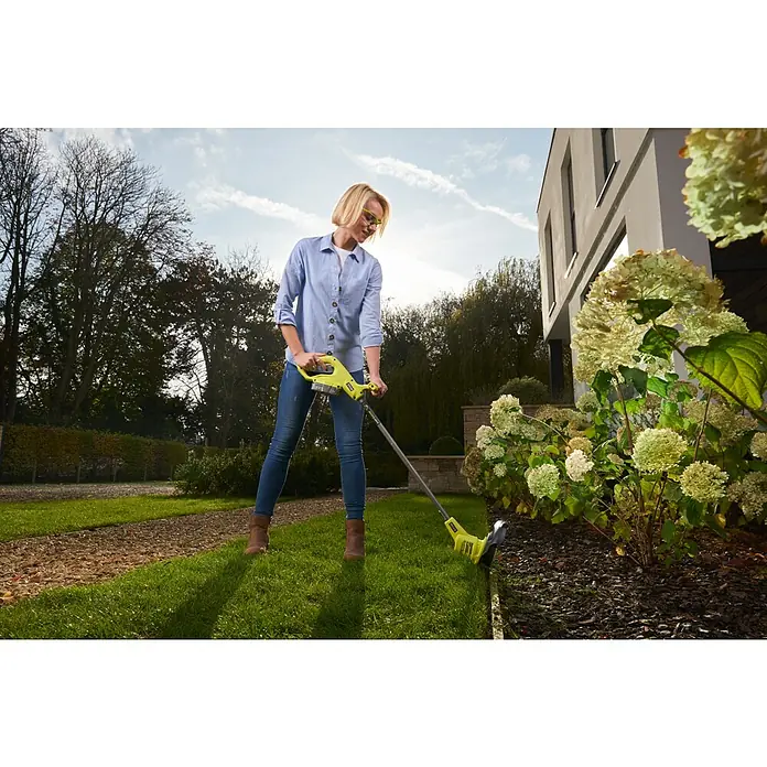 Ryobi ONE+ Akku-Rasenmäher-Set Kombo-Kit RLM1833BLT1825M mit Akku-Rasentrimmer - 1 Akku, 4 Ah - Eine Frau trimmt den Rasen mit einem gelben Rasentrimmer von Ryobi vor einem Blumenbeet, um einen gepflegten Garten zu erhalten.