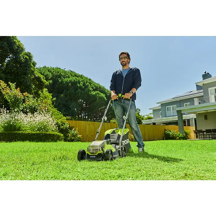 Ryobi ONE+ Akku-Rasenmäher-Set Kombo-Kit RLM1833BLT1825M mit Akku-Rasentrimmer - 1 Akku, 4 Ah - Ein Mann mäht den Rasen mit einem grünen Ryobi Rasenmäher vor einem Haus mit einem Holzzaun.