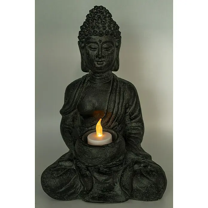 Buddha - 19 x 13 x 28 cm, Schwarz - Eine Buddha-Statue aus dunklem Stein hält eine leuchtende Kerze in ihren Händen, die friedliche Kontemplation und spirituelle Ruhe ausstrahlt.