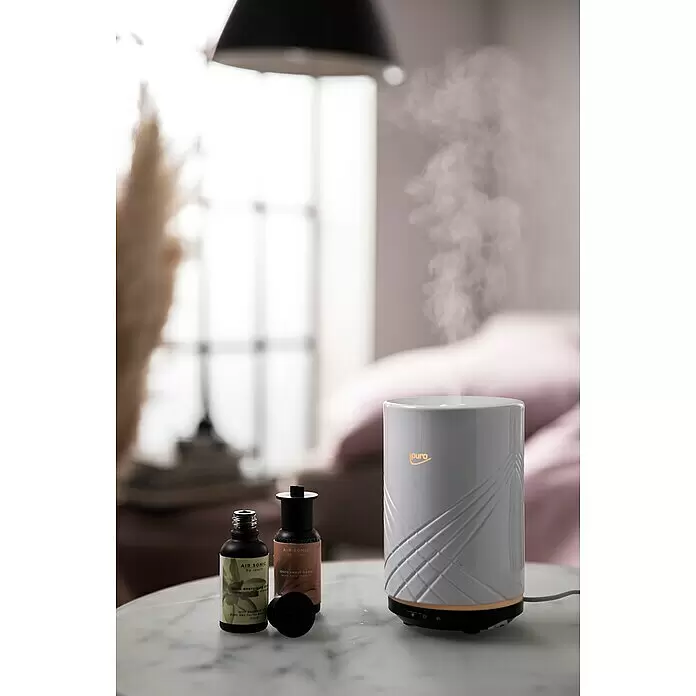 Ipuro Air Sonic Difusor eléctrico Elegance - Blanco - Difusor de aromas blanco con niebla y dos botellas de aceites esenciales sobre mesa de mármol.