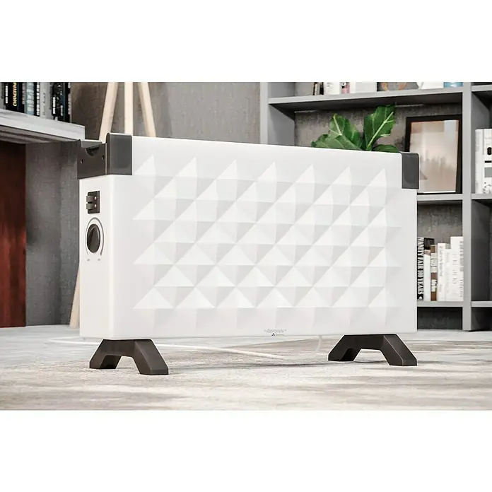 Voltomat HEATING Convector Rombo mini - 2.000 W, Habitaciones de hasta 25 m², Blanco/Negro - Primer plano de un calefactor blanco con patrón triangular y patas negras, sobre una alfombra.