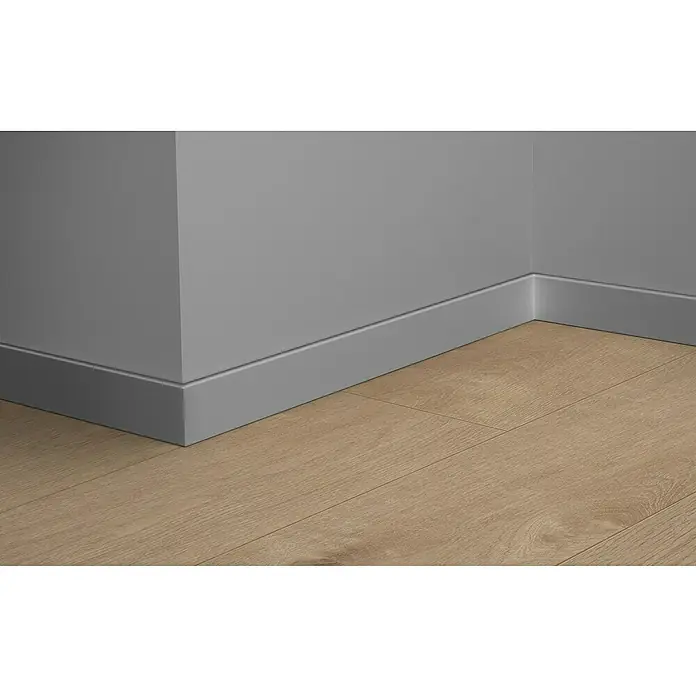 LOGOCLIC Sockelleiste Element Pro K58 C - 240 cm x 18 mm x 58 mm, Silber - Nahaufnahme einer grauen Sockelleiste, die an einer grauen Wand entlangläuft und auf einen hellbraunen Holzboden trifft.