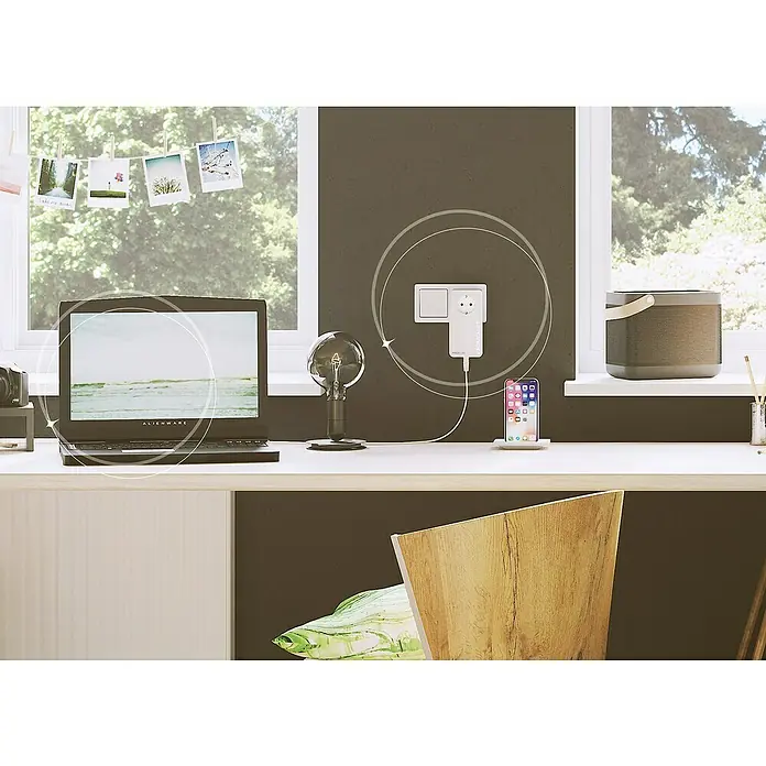 Devolo Erweiterungsadapter Magic 1 LAN - 1 Stk., Datenübertragung: WLAN, Passend für: devolo Magic-Reihe - Ein weißer Devolo Magic 1 WiFi Mini Adapter steckt in einer Steckdose und lädt ein Smartphone, während ein Laptop daneben steht.