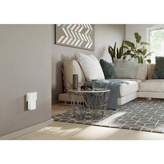 Devolo Erweiterungsadapter Magic 2 WiFi next - 1 Stk., Passend für: devolo Magic-Reihe - Ein weißer WLAN-Repeater ist an einer grauen Wand in einem Wohnzimmer angebracht. Der Repeater verbessert die WLAN-Abdeckung im Raum.