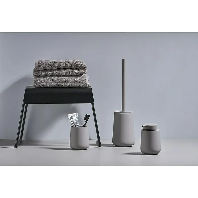 Zone Denmark Nova One WC-Bürstengarnitur - ABS-Kunststoff, Gull Grey - Modernes Badezimmer-Set in Grau: Handtücher auf einem Hocker, Zahnputzbecher mit Zahnpasta und Bürste, Toilettenbürste und Seifenspender.