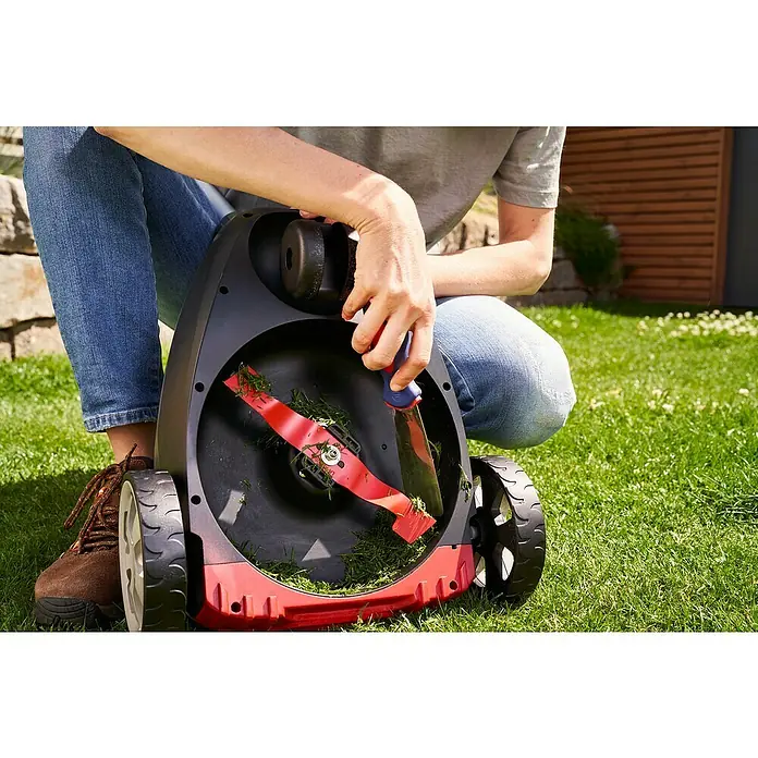 AL-KO Bosch Home & Garden Compatible Akku-Rasenmäher 22.4 LI Comfort - 18 V, 1 Akku, 2,5 Ah - Eine Person wartet einen Rasenmäher mit einer roten Klinge, während sie ein Messer benutzt, um das Gras zu entfernen.