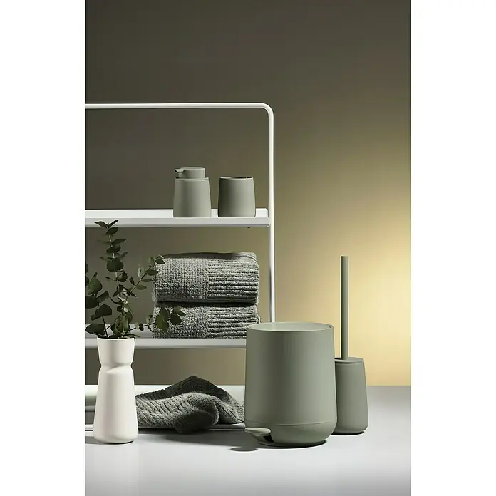Zone Denmark Nova One Kosmetikeimer - 3 l, Kunststoff, Matcha Green - Stilvolle Badezimmer-Accessoires in sanften Farbtönen arrangiert vor einem modernen Regal mit Handtüchern und Pflanze.