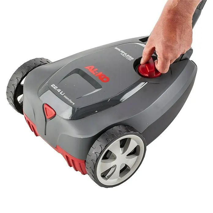 AL-KO Bosch Home & Garden Compatible Akku-Rasenmäher 22.4 LI Comfort - 18 V, 1 Akku, 2,5 Ah - Nahaufnahme eines AL-KO Rasenmähers mit einem roten Knopf, der von einer Hand gedrückt wird, vor einem schwarzen Hintergrund.