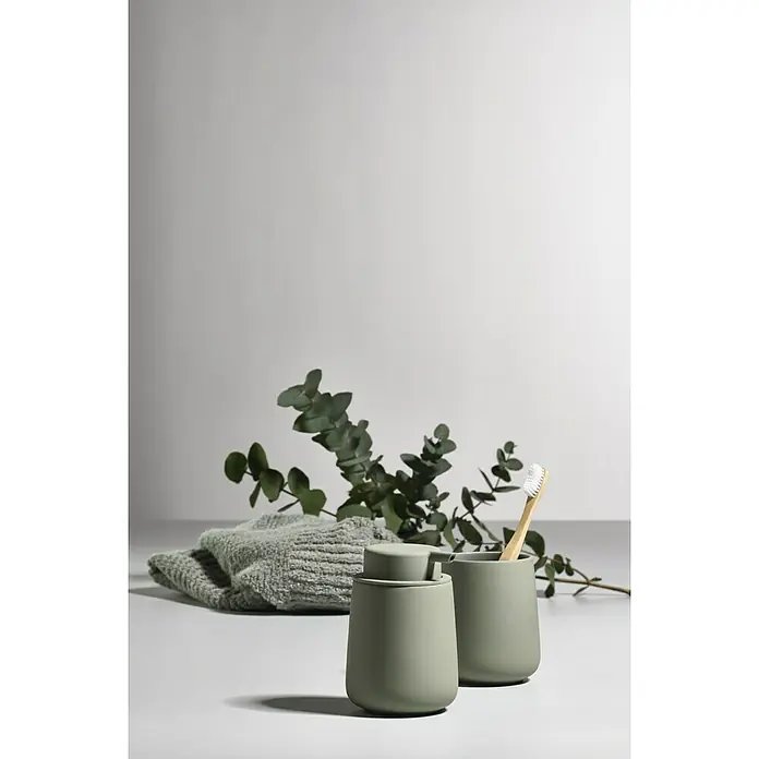 Zone Denmark Nova One Seifenspender - ABS-Kunststoff, Matcha Green - Seifenspender und Becher mit Zahnbürste aus Keramik, neben einem grünen Handtuch und Eukalyptuszweigen.