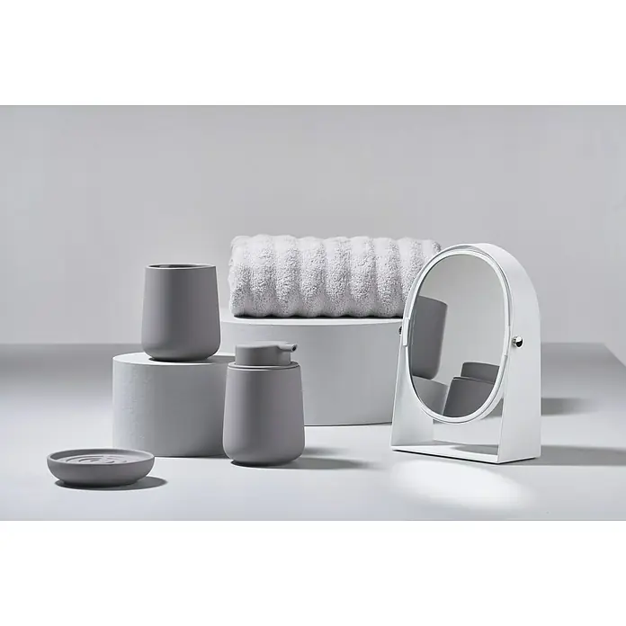 Zone Denmark Nova One Seifenschale - Keramik, Gull Grey - Stilleben mit Badutensilien in neutralen Farben, darunter ein Seifenspender, ein Becher, eine Schale und ein Spiegel, auf weißen Oberflächen.