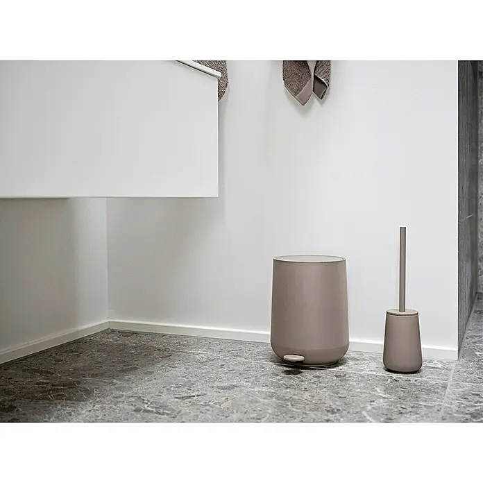 Zone Denmark Nova One Kosmetikeimer - 3 l, Kunststoff, Taupe - Ein eleganter, beiger Treteimer und eine passende WC-Bürste stehen auf einem grauen Marmorboden in einem modernen Badezimmer.
