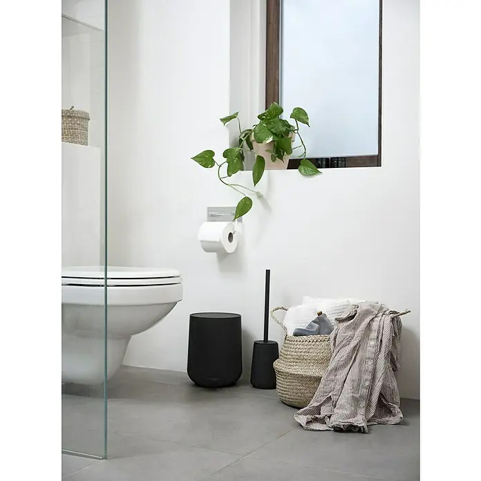 Zone Denmark Nova One Kosmetikeimer - 3 l, Kunststoff, Black - Badezimmer-Szene mit einer Toilette, einem schwarzen Mülleimer, einer WC-Bürste und einem Korb mit Handtüchern und Kleidung für ein sauberes Ambiente.