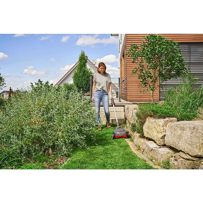 AL-KO Bosch Home & Garden Compatible Akku-Rasenmäher 22.4 LI Comfort - 18 V, 1 Akku, 2,5 Ah - Frau benutzt einen Rasenkehrer im Garten. Das Gerät ist grau mit roten Akzenten und dient zur Reinigung von Rasenflächen.