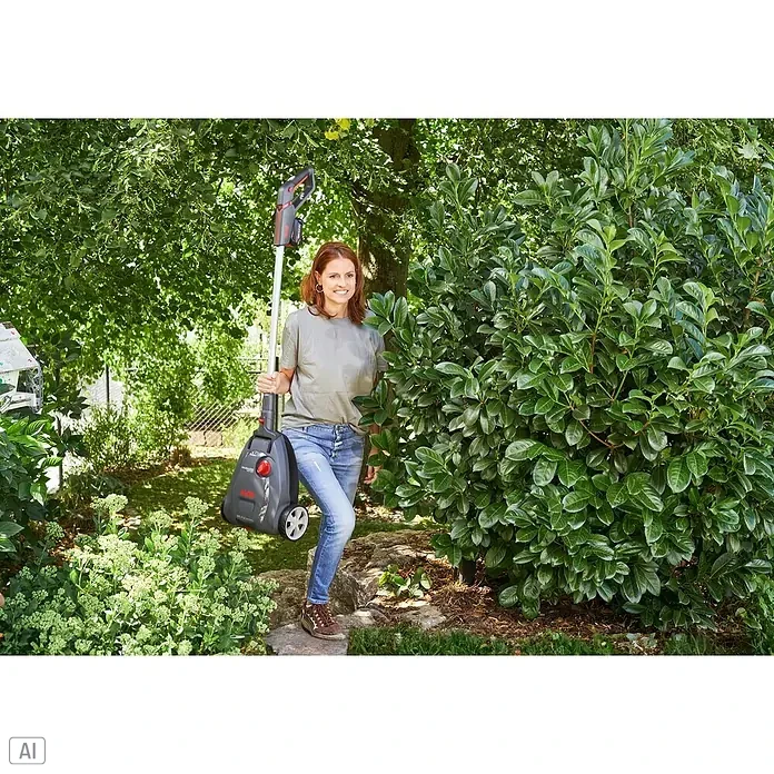 AL-KO Bosch Home & Garden Compatible Akku-Rasenmäher 22.4 LI Comfort - 18 V, 1 Akku, 2,5 Ah - Frau im Garten hält einen Akku-Rasentrimmer der Marke VARO in der Hand, umgeben von üppigem Grün und Sträuchern.