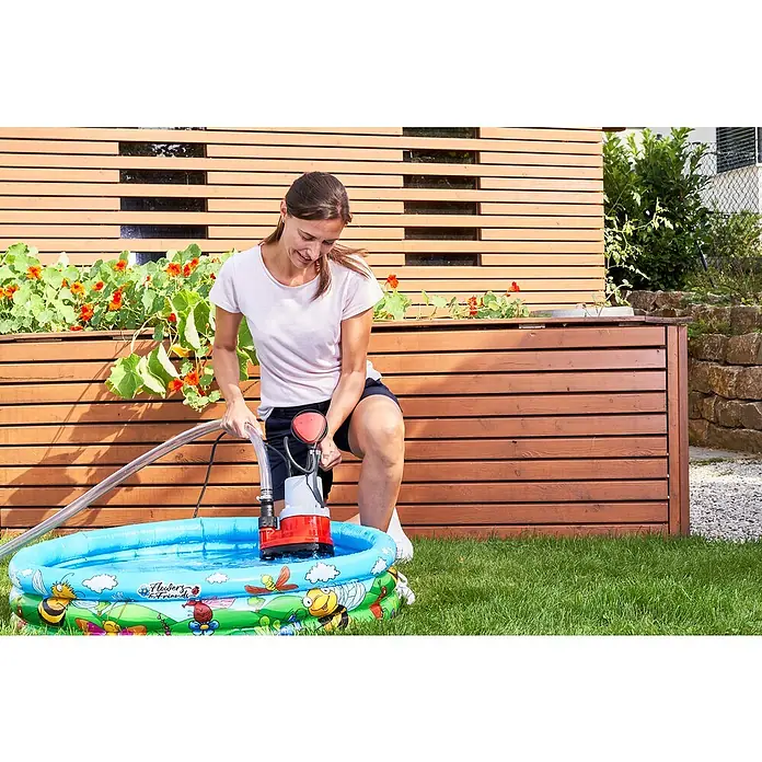 AL-KO Klarwasser-Tauchpumpe SUB 8500 EASY - 290 W, Max. Fördermenge: 8.000 l/h - Eine Frau entleert mit einer AL-KO Tauchpumpe einen Pool im Garten. Die Pumpe ist rot und grau und steht im Wasser des Pools.