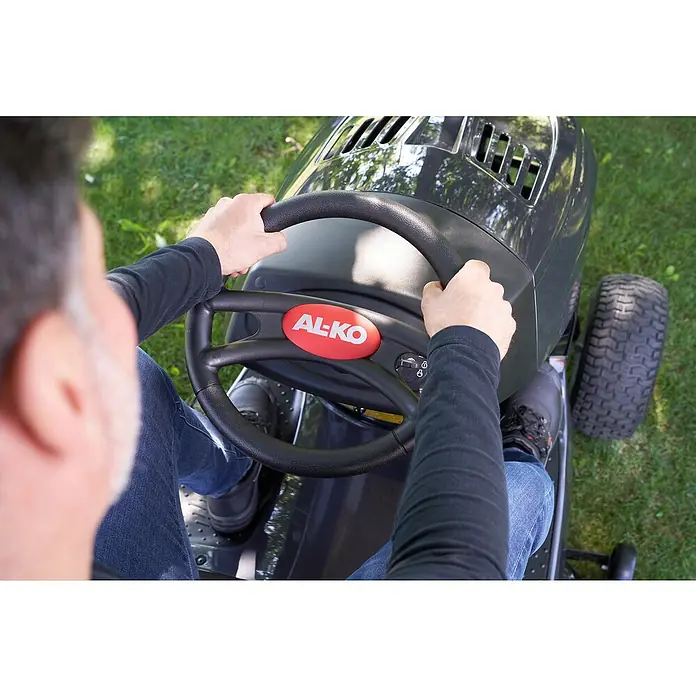 AL-KO Comfort Rasentraktor 18-103.4 HD-A V2 - 568 cm³, Schnittbreite: 103 cm - Nahaufnahme eines AL-KO Aufsitzmähers mit einer Person am Steuer. Das rote AL-KO-Logo ist gut sichtbar.