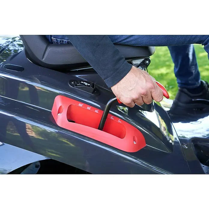 AL-KO Comfort Rasentraktor 18-103.4 HD-A V2 - 568 cm³, Schnittbreite: 103 cm - Ein Mann bedient den Geschwindigkeitshebel eines Aufsitzmähers mit roter Bedienung und schwarzem Hebel vor einem grünen Hintergrund.