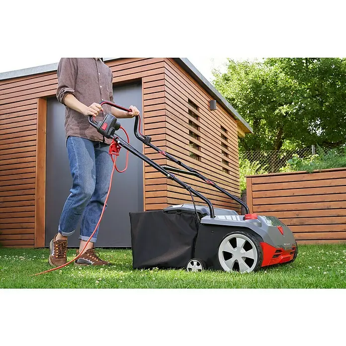AL-KO Easy Elektro-Vertikutierer-Lüfter 38.4 E Combi Care - 1.400 W, Arbeitsbreite: 38 cm - Ein Mann benutzt einen Rasenlüfter im Garten. Der Rasenlüfter ist grau, schwarz und rot und hat einen Fangkorb.