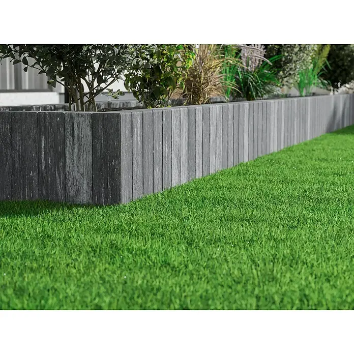 Diephaus Palisade / Mauerstein Laredo - 40 x 10 x 10 cm, Weiß/Schwarz, Beton - Das Foto zeigt eine graue Rasenkante aus Holz, die einen grünen Rasen von einem bepflanzten Bereich trennt. Die Kante ist sauber und modern gestaltet.