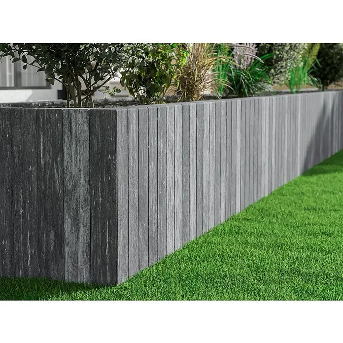Diephaus Palisade / Mauerstein Laredo - 80 x 10 x 10 cm, Weiß/Schwarz, Beton - Detailansicht einer grauen, erhöhten Gartenbeetumrandung aus Holzverbundmaterial mit üppigem Grünpflanzenwuchs und saftigem Rasen.