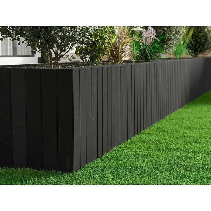 Diephaus Palisade / Mauerstein Laredo Meso - 80 x 10 x 10 cm, Basalt, Beton - Das Bild zeigt einen erhöhten, schwarzen Pflanzkasten aus Holzlamellen, bepflanzt mit verschiedenen Grünpflanzen, vor einem grünen Rasen.